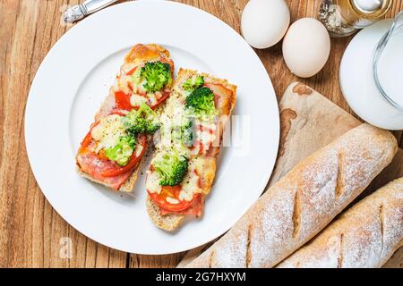 Aprire il panino con prosciutto, mozzarella e pomodori sul tavolo da cucina, fondale focus Foto Stock