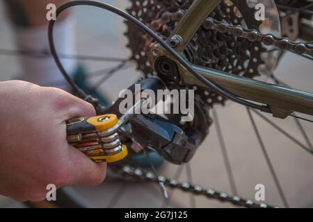 Primo piano di un uomo con un cacciavite multitool, fissando la bicicletta Foto Stock