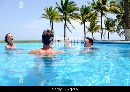 Gruppo giovane di amici che si divertano nella piscina vicino alla spiaggia Foto Stock