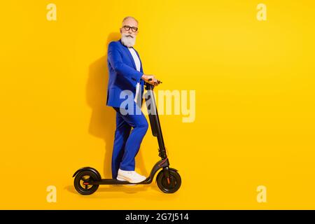 Profilo a lunghezza intera con vista laterale di un elegante e funky scooter eco kick isolato su uno sfondo di colore giallo brillante Foto Stock