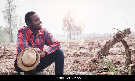 Coltivatore africano sedersi e pensare a preparare il suolo per planting. Agriculture o concetto di coltivazione Foto Stock