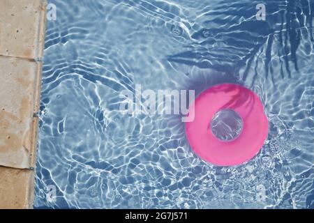 Anello di galleggiamento della piscina rosa che galleggia in una rinfrescante piscina blu. Vista dall'alto Foto Stock