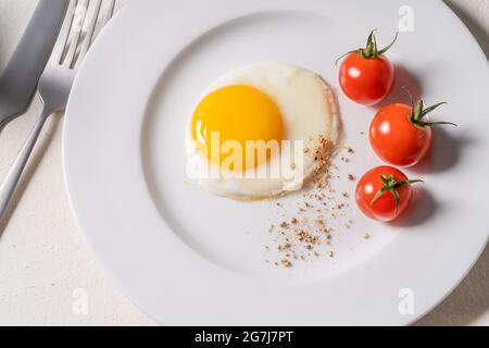 Tavolo da pranzo per la colazione. Caffè, latte, uova fritte, pomodori ciliegini su tovaglia di lino Foto Stock