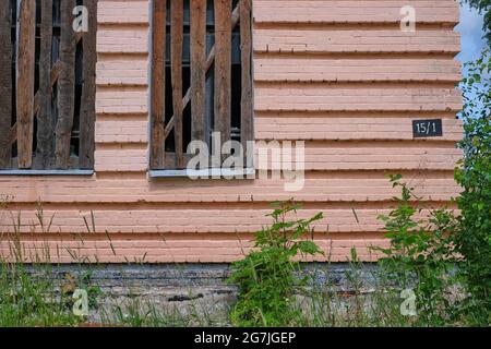 Il bordo di un edificio abbandonato con due finestre a bordo e un cartello con il numero della casa Foto Stock