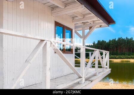 Cabina di bagnino bianca in legno situata sulla spiaggia di sabbia accanto al lago in una bella giornata di sole Foto Stock