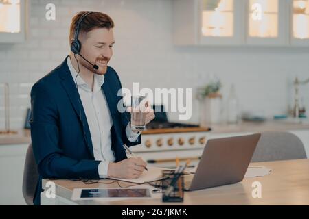 Felice giovane uomo che parla con il suo collega durante la riunione online da remoto Foto Stock