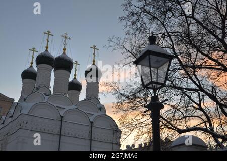 Lampione d'epoca con moderne lampade a LED vicino alla vecchia chiesa sullo sfondo del cielo del tramonto invernale Foto Stock