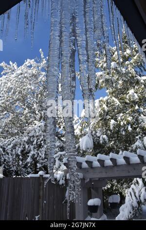 Colpo di closeup della formazione di icicle dal tetto con gocce d'acqua che cadono mentre la temperatura diventa più calda durante l'inverno. Foto Stock