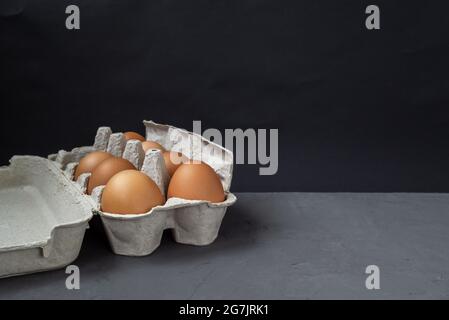 Scatola di uovo. Un vassoio pieno di uova marroni su sfondo scuro in una confezione standard Foto Stock