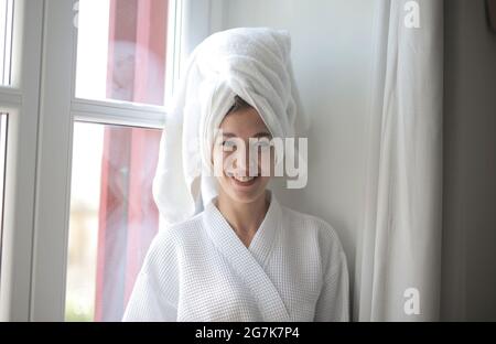 Ritratto di una giovane donna sorridente in un accappatoio con capelli avvolti in un asciugamano Foto Stock