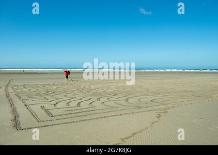 Uomo che fa un labirinto di spiaggia a Cannon Beach, Oregon Foto Stock
