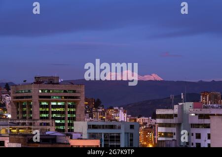 Quito città con il vulcano Antisana durante l'ora blu, Ecuador. Foto Stock