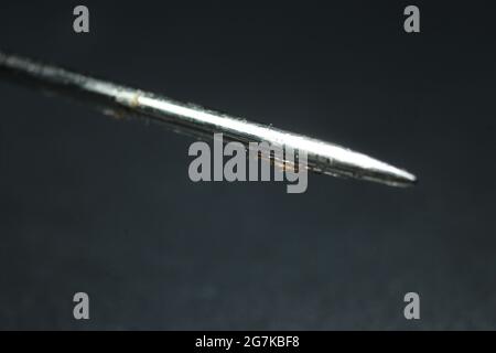 Macro shot di un ago da cucire isolato su sfondo nero Foto Stock
