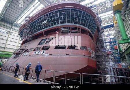 14 luglio 2021, Meclemburgo-Pomerania occidentale, Wismar: I costruttori osservano l'assemblaggio del sistema di propulsione della nave a poppa della nave da crociera 'Global Dream' in costruzione nella banchina del cantiere MV. Il moderno motore da 230 tonnellate con elica da 5.90 metri e motore elettrico da 19,000 kilowatt può essere ruotato di 360 gradi. La nave, destinata al mercato asiatico e che trasporta più di 5,000 passeggeri, è lunga 342 metri e alta 57 metri. La nave da crociera Global Class è fissata per diventare la più grande nave da crociera nel mondo in termini di capacità dei passeggeri. Foto: Jens Büttner/dp Foto Stock