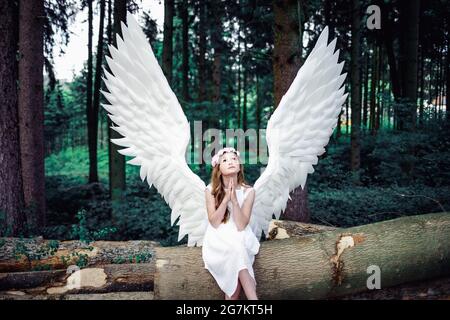 Primo piano di una ragazza bionda caucasica in costume di ali d'angelo in un parco Foto Stock