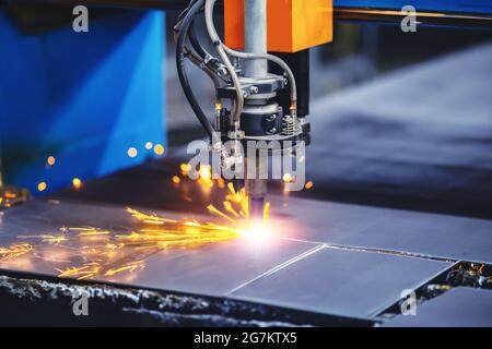 La macchina CNC per il taglio al plasma taglia il materiale metallico con scintille, background industriale. Foto Stock