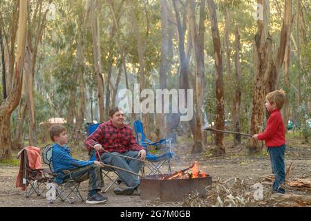 Bambini con il padre che brucia fuoco a Kuitpo foresta campeggio vacanze terra scuola Foto Stock