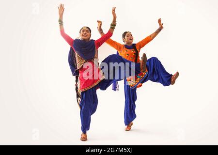 Due ballerini Giddha che eseguono un passo di danza con le mani in su e una gamba in alto. Foto Stock