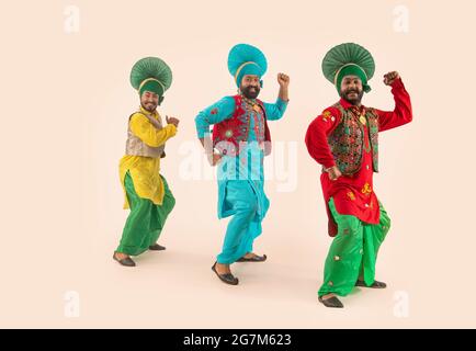 Tre ballerini Bhangra che eseguono un passo di danza con gesti a mano. Foto Stock