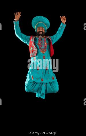 Un ballerino di Bhangra che salta con le mani per eseguire un passo di danza. Foto Stock