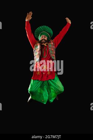 Un ballerino di Bhangra che salta con le mani per eseguire un passo di danza. Foto Stock