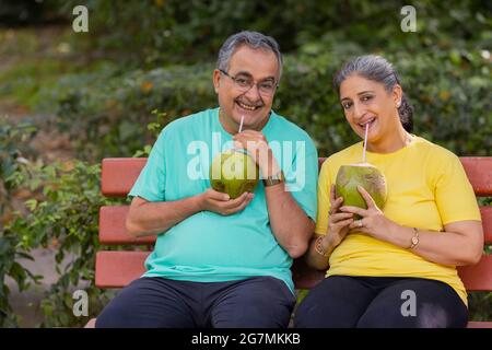 UNA COPPIA FELICE CHE GUARDA LA MACCHINA FOTOGRAFICA MENTRE BEVE L'ACQUA DI COCCO Foto Stock