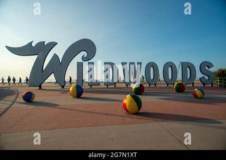 Wildwood, Stati Uniti. 15 luglio 2021. La gente cammina sulla passerella dietro il cartello Wildwoods in un caldo giorno d'estate Giovedi, 15 luglio 2021 a Wildwood, New Jersey. Le temperature sono attese negli anni '90 per tutto il resto di questa settimana. Credit: William Thomas Cain/Alamy Live News Foto Stock