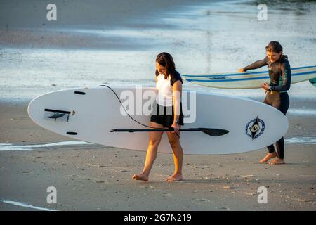 North Wildwood, Stati Uniti. 15 luglio 2021. Arianna Qira, 27 e Makenzie Franco, 27, di Capo Ovest, possono uscire dall'Oceano Atlantico dopo una sessione di paddle board al mattino presto in un caldo giorno estivo giovedì 15 luglio 2021 a North Wildwood, New Jersey. Le temperature sono attese negli anni '90 per tutto il resto di questa settimana. Credit: William Thomas Cain/Alamy Live News Foto Stock