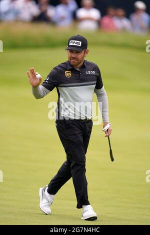 Louis Oosthuizen del Sud Africa riconosce la folla sulla strada per una partita di 6 persone durante il giorno uno degli Open al Royal St George's Golf Club di Sandwich, Kent. Data immagine: Giovedì 15 luglio 2021. Foto Stock