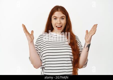 Ritratto di donna zenzero eccitata gioisce da notizie impressionanti, mani clap e sguardo sorpreso stupito alla macchina fotografica, festeggiando, sentire grande annuncio Foto Stock