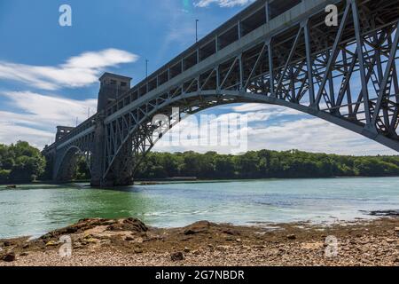 Il Ponte Britannia dalla costa dello stretto di Menai a bassa marea, Anglesey, Galles del Nord Foto Stock