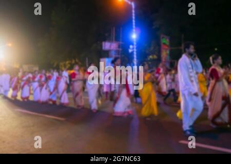 Immagine offuscata di uomini indù bengalesi vestiti con abiti indiani tradizionali rossi e bianchi, stanno camminando al carnevale di Durga Puja sulla Red Roa Foto Stock