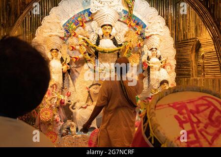 KOLKATA , INDIA - 27 SETTEMBRE 2017 : il sacerdote indù adorava la dea Durga mentre dhaakis (batteristi) si esibiva nel suo backside. Durga Puja festival Foto Stock