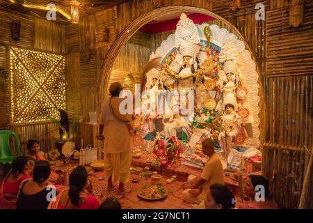 KOLKATA , INDIA - 27 SETTEMBRE 2017 : il sacerdote indù adorava la dea Durga mentre dhaakis (batteristi) si esibiva nel suo backside. Durga Puja festival Foto Stock
