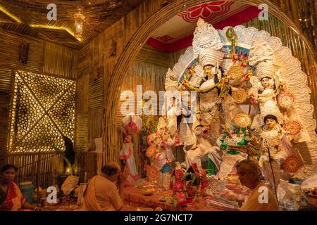 KOLKATA , INDIA - 27 SETTEMBRE 2017 : il sacerdote indù adorava la dea Durga mentre dhaakis (batteristi) si esibiva nel suo backside. Durga Puja festival Foto Stock
