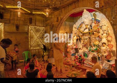 KOLKATA , INDIA - 27 SETTEMBRE 2017 : il sacerdote indù adorava la dea Durga mentre dhaakis (batteristi) si esibiva nel suo backside. Durga Puja festival Foto Stock