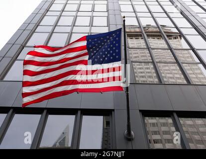 Bandiera americana sventolando di fronte ad un grattacielo a New York City. Foto Stock