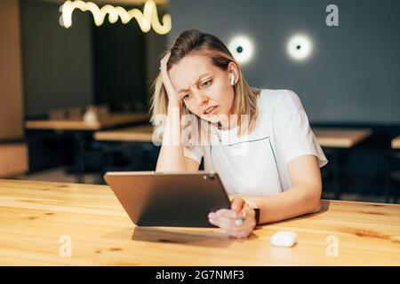 Una donna stressante e sconvolta guarda lo schermo di un tablet digitale. Foto Stock