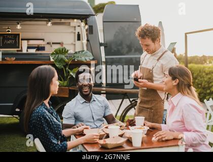 Persone multirazziali che ordinano cibo a camion di cibo all'aperto - Focus sulla faccia africana uomo Foto Stock