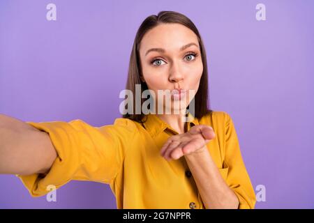 Ritratto fotografico di donna sorridente che invia bacio aria prendendo selfie isolato su sfondo di colore viola pastello Foto Stock