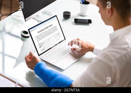 Copertura di risarcimento danni al lavoratore con braccio rotto. Utilizzo di un portatile Office Foto Stock