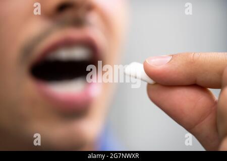 L'uomo che usa il Gum della nicotina per uscire fumare. Terapia di sostituzione della nicotina Foto Stock