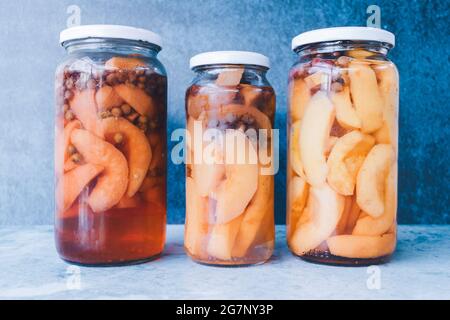 Vasetti di vetro di frutta conservata in casa, su sfondo blu. Concetto di nutrizione. Foto Stock