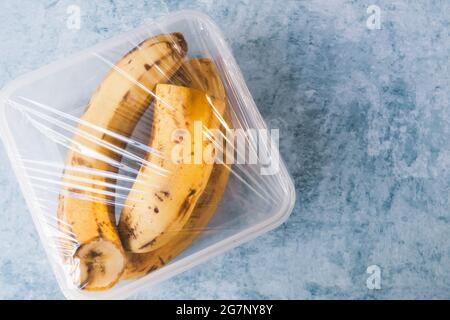 Uso di pellicola alimentare per la conservazione delle banane in frigorifero. Vista dall'alto Foto Stock