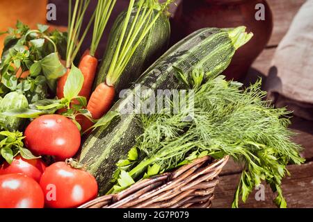 Fuoco selezionato, composizione alimentare con verdure locali, ortaggi in un cesto: Pomodori, cetrioli, zucchine, carote, prezzemolo, aneto e basilico. Concetto di Foto Stock