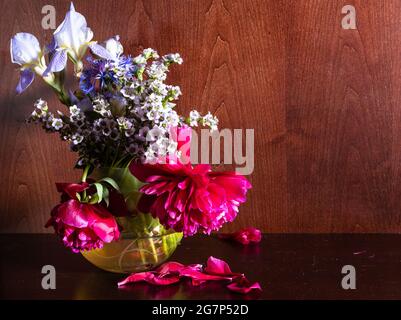 fiori appassiti in vaso su fondo di legno marrone scuro Foto Stock