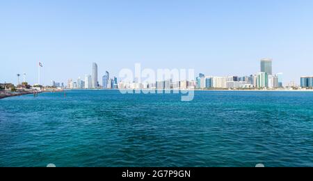 Vista panoramica del centro di Abu Dhabi. Paesaggio urbano in una giornata estiva, grattacieli e bandiera nazionale degli Emirati Arabi Uniti sono sulla costa del mare Foto Stock