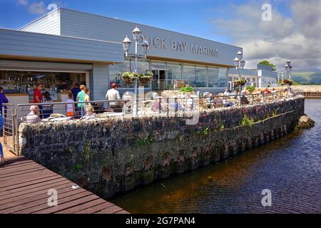 Le persone che godono del sole sulle rive del Loch Lomond presso il caffè di Duck Bay Marina Foto Stock