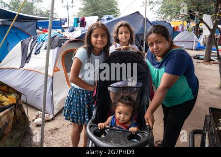 Reynosa, Messico. 15 luglio 2021. Una famiglia pone per la macchina fotografica al bordo della piazza accanto ad una piccola cucina che soddisfa le esigenze dei migranti. Credit: Lexie Harrison-Cripps/Alamy Live News Foto Stock