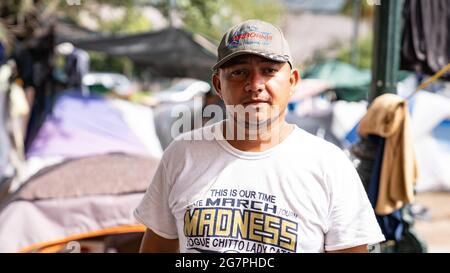 Reynosa, Messico. 15 luglio 2021. Un uomo migrante posa per la telecamera di fronte a molte tende nella piazza principale. Credit: Lexie Harrison-Cripps/Alamy Live News Foto Stock